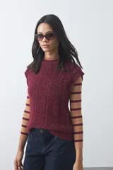 Chaleco tejido de punto con textura suave, color bordó, diseño sin mangas, cuello redondo y terminaciones acanaladas.