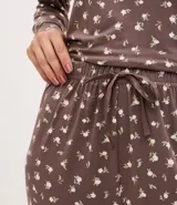 Pantalón de pijama tipo jogger, color marrón con estampado floral pequeño en blanco. Presenta cintura elástica con lazo de ajuste frontal y puños ajustados en los tobillos.