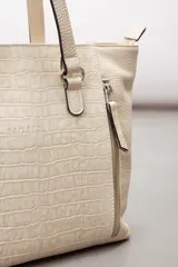 Cartera de cuero vacuno color marrón, de diseño amplio con paneles combinados de diferentes texturas y un panel central con relieve de cocodrilo. Cuenta con cierre frontal vertical y asas de hombro.