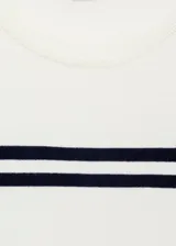 Jersey de punto fino color crudo, con cuello redondo y mangas cortas. Presenta dos líneas horizontales oscuras en el pecho y las mangas.