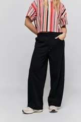 Babucha de calce relajado color negro, con cintura elastizada, cordón de ajuste y bolsillos laterales. Presenta un diseño de pernera amplia y cómoda.