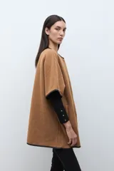 Capa color tostado con vivos en contraste de color negro, cierre frontal con un botón grande y un bolsillo lateral.