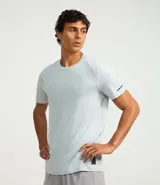 Remera deportiva de hombre con tecnología dry fit, cuello redondo y manga corta. Presenta un diseño liso en color beige con una pequeña etiqueta decorativa en el dobladillo.