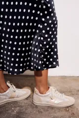 Falda midi de poliéster color negro con estampado de lunares blancos.