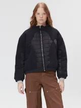 Campera crop de corte boxy y color negro, forrada en corderito, con parches capitoneados en el pecho y las mangas. Cuenta con cierre frontal metálico, cuello alto, puños y bajo elastizados, y detalle de logo bordado en hilo en el pecho.