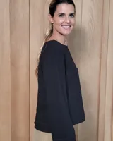 Remera de manga larga color blanco, con cuello redondo y dos bolsillos frontales tipo parche. Presenta un corte recto y holgado con un diseño minimalista.