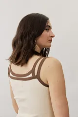 Musculosa de tejido rib color beige con detalles en marrón oscuro en el escote y doble tirante fino. Presenta un pequeño texto estampado en el pecho.