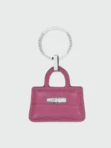 Llavero Longchamp con dije en forma de bolso Le Roseau de cuero color fucsia con textura de cocodrilo y herrajes plateados.