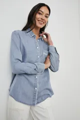 Camisa celeste de denim tencel, de corte holgado, con cuello clásico, cierre frontal con botones y bolsillo en el pecho con detalle bordado.