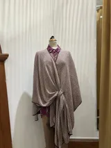 Ruana de lana estampada en tonos lavanda y ocre, con ribetes de seda y presilla para sujetar.