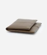 Billetera plegable pequeña Satinato de material sintético en color marrón, con diseño de pespuntes verticales y cierre con solapa.