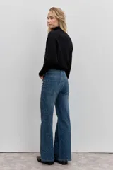 Pantalón de jean corte wide leg, color azul medio, con detalle de strass aplicado en toda la superficie frontal. Cuenta con tiro medio, cierre frontal con botón y bolsillos laterales y traseros.