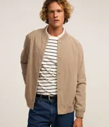 Campera bomber masculina de terciopelo cotelé color beige, con cuello redondo, mangas largas, cierre frontal de botones forrados, bolsillos laterales y terminaciones de elástico en puños y cintura.