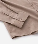 Camisa de manga larga con cuello inglés y cierre frontal de botones, confeccionada en tricolina de algodón color beige.