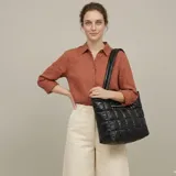 Bolso shopper negro de nylon acolchado con diseño capitoné en cuadrados. Cuenta con doble asa de hombro y cierre superior.