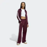 Pantalón deportivo Adidas Firebird de corte holgado, color bordó con las icónicas tres rayas laterales en blanco y logo del trébol bordado. Presenta cintura de tiro medio y diseño de pierna ancha.