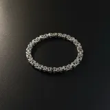 Pulsera de acero plateado con eslabones tipo bizantino.