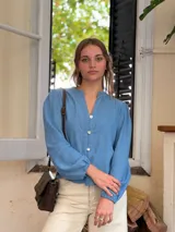 Cartera bandolera de cuero color chocolate, con solapa frontal decorada con costuras artesanales a la vista. Cuenta con correa larga ajustable y herrajes metálicos en tono bronce.