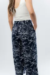 Pantalón de corte culotte y tiro medio, confeccionado en viscosa con estampado de hojas blancas sobre fondo color miel. Presenta una silueta amplia y fluida, con cintura elástica en la parte posterior y bolsillos laterales.