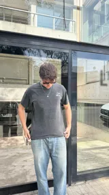 Remera negra con efecto gastado, corte oversized y estampado blanco en la espalda con las frases 'Crafted for the future', 'Worldwide service Saint Global' y 'Studios since 2025'.