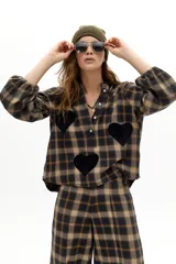 Camisa oversized de algodón con estampado de cuadros en tonos marrones y azules. Presenta cuello mao, cierre frontal con botones de nácar, mangas largas abullonadas con puños elásticos y apliques decorativos en forma de corazón de lana en el frente y las mangas.