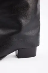 Bota de caña alta confeccionada en cuero vacuno, con diseño de solapa superior y taco bajo cuadrado.