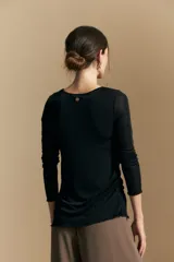 Top de manga larga con textura suave y leve brillo. Presenta una silueta al cuerpo, tajos laterales y terminaciones onduladas en el ruedo.