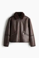 Campera de tejido revestido con acabado efecto cuero envejecido, cuello de solapa con forro de sherpa, cierre frontal y bolsillos laterales con cierre.