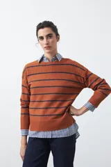 Sweater de tejido de punto con diseño de rayas horizontales en tonos bordó y rojo. Presenta cuello redondo, mangas largas con hombros caídos y terminaciones acanaladas en puños, cuello y ruedo.