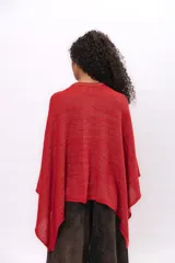 Ruana tejida de punto en algodón con destellos de lurex, de corte asimétrico y escote en V. Presenta una etiqueta de cuero con el logo de la marca en el frente.