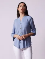 Camisa celeste texturada marca Ninety, con cuello a la base, escote en V y abertura central con botones. Tiene un bolsillo en el pecho y mangas tres cuartos regulables con presilla y botón.