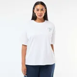 Camiseta blanca de corte oversize, con mangas cortas y un pequeño estampado gráfico verde en el pecho.