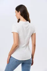 Remera polo de algodón color beige con mangas cortas, escote en V y cuello camisero. Presenta delicados mini bordados florales distribuidos en toda la prenda.