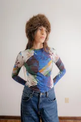 Remera de manga larga confeccionada en algodón elastizado, con cuello redondo y diseño ajustado al cuerpo. Presenta un estampado de rombos finos con motivos florales en tonos azules sobre una base de color marrón oscuro.