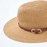 Sombrero de paja estilo panamá color beige, con ala ancha y una cinta marrón decorativa alrededor de la copa con hebilla metálica dorada.