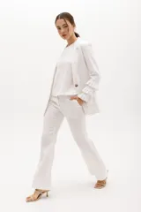 Blazer color beige confeccionado en lino, con cuello solapa, cierre frontal con un botón y mangas largas con volantes en capas.