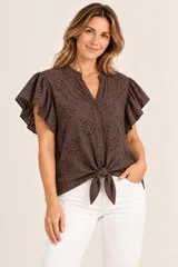 Blusa marrón de algodón con diseño de broderie, mangas cortas con volados y cierre frontal de botones con detalle de nudo en el dobladillo.