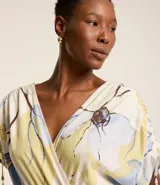 Vestido evasê midi de viscolino con estampado floral, escote en V cruzado, mangas cortas con lazos y corte en la cintura.
