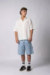 Camisa de manga corta confeccionada en una mezcla de lino y viscosa, de color blanco. Presenta un diseño de calce regular con cuello plano y cierre frontal de botones.