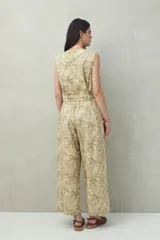 Mono largo sin mangas de algodón con estampado de hojas en tonos verde y beige. Tiene cuello en V, cierre frontal con botones, bolsillos laterales y cinturón de lazo.