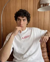 Remera de corte oversize color beige, con estampa estilo pixel art en la espalda que representa a un boxeador con guantes rojos y estrellas alrededor de la cabeza.