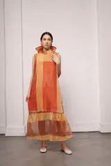 Vestido largo color naranja con estampado a cuadros, cuello alto con volados y sin mangas. Incluye un viso liso por debajo al tono.