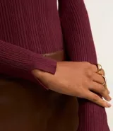 Suéter de punto acanalado color beige, con cuello redondo y mangas largas. Confeccionado en tejido tricot con textura suave y ajuste al cuerpo.