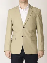 Saco sport color beige, de algodón, con forro completo interno y cierre frontal de dos botones. Presenta solapas de muesca, bolsillos de parche en la parte inferior y un bolsillo superior con ojal.