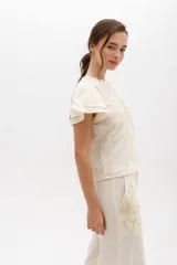 Blusa negra de lino con bordado en relieve de formas orgánicas, mangas cortas con volados y terminaciones desflecadas.