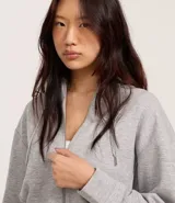 Saco color crema, de corte slim, confeccionado en algodón con viscosa certificada, con cuello con capucha y cordón ajustable, cierre frontal con cremallera y forro de fleece.