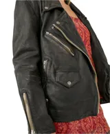 Chaqueta de cuero negra estilo motoquera con cierre frontal asimétrico, tres bolsillos con cierre y un bolsillo con botón.