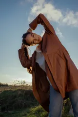 Gabardina marrón de cuero ovino italiano, con cuello camisero, cierre frontal con botones, mangas largas y corte recto.