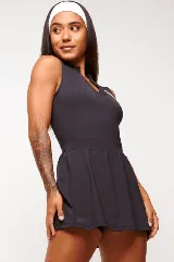 Vestido deportivo negro sin mangas, con escote en V y logo estampado en el pecho. Falda corta con short interno y bolsillos laterales. Incluye protección UV50+.