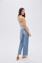 Pantalón de jean azul de corte recto y tiro medio, con detalles de estrellas bordadas a lo largo de los laterales externos de las piernas.